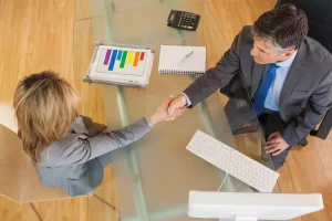 Dos personas estrechando la mano durante una reunión de trabajo